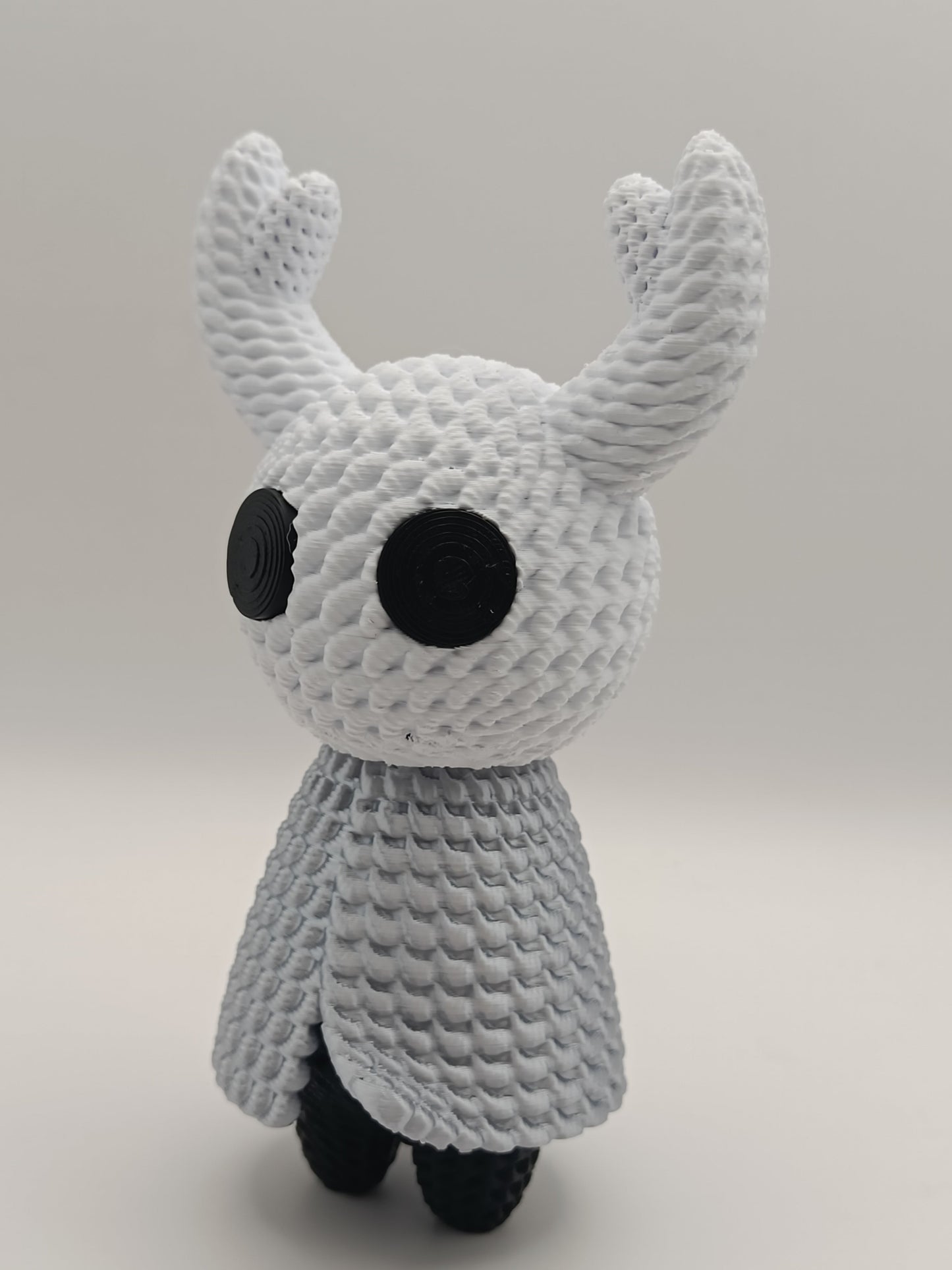 Vista laterale della statua Hollow Knight con mantello argentato