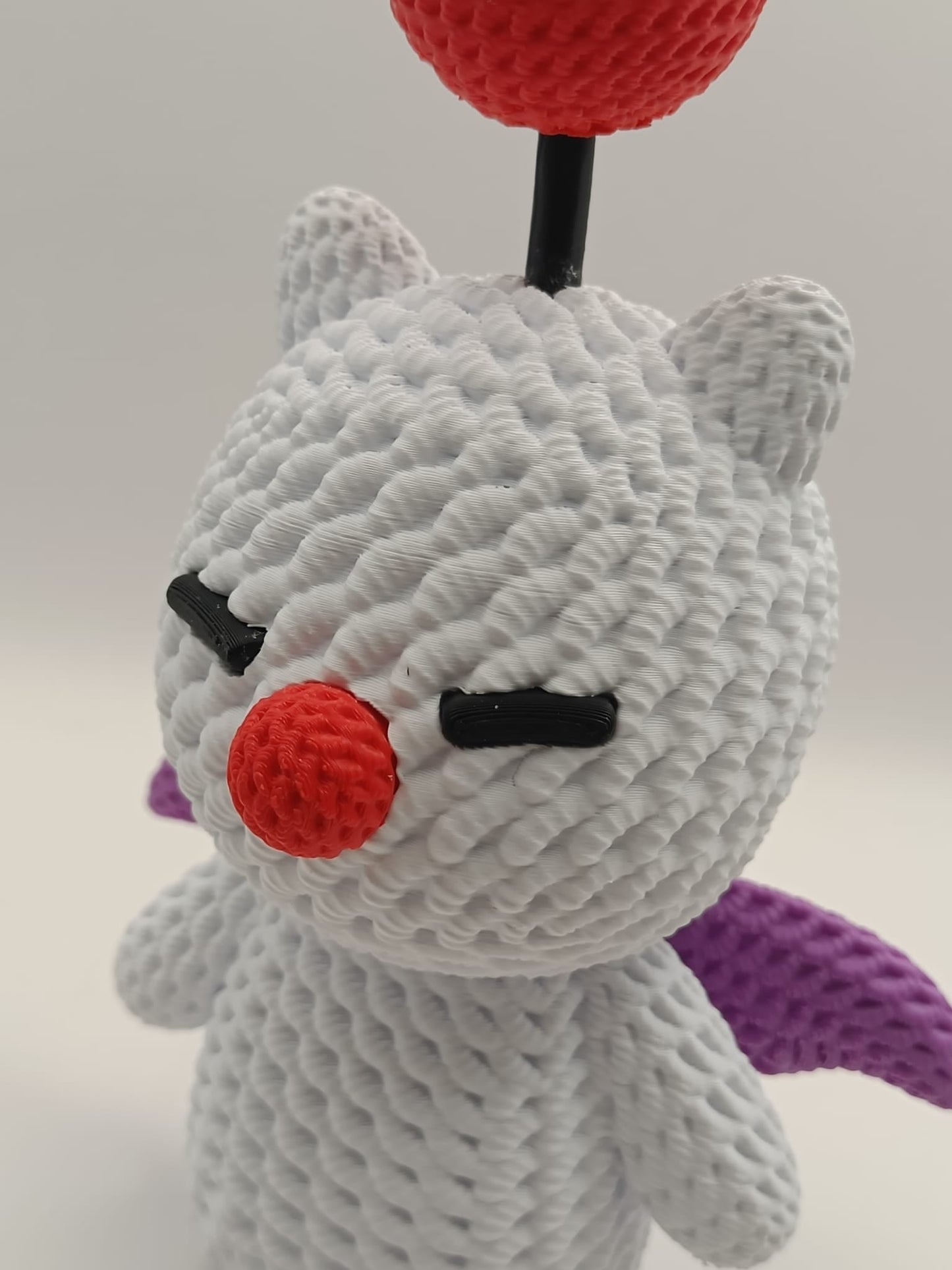 Dettaglio ravvicinato del viso del Moogle crochet con pompon rosso