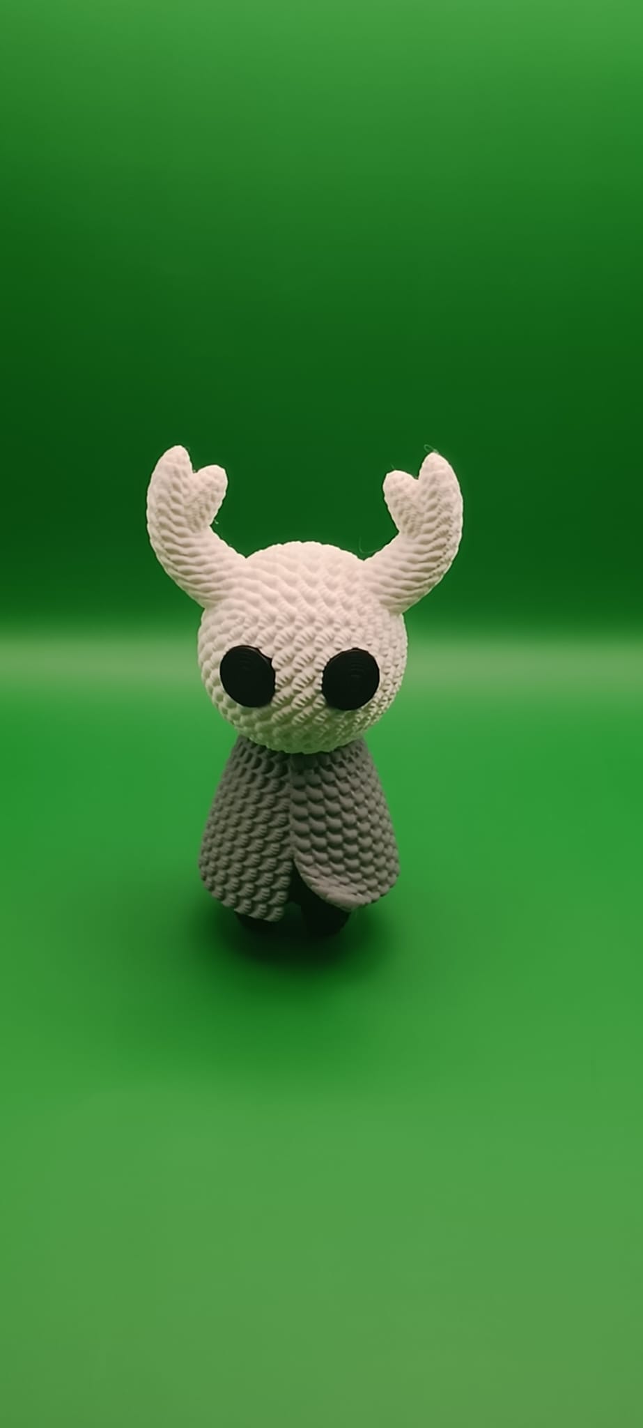 Statua Hollow Knight, stile crochet con sfondo verdee luce bianca