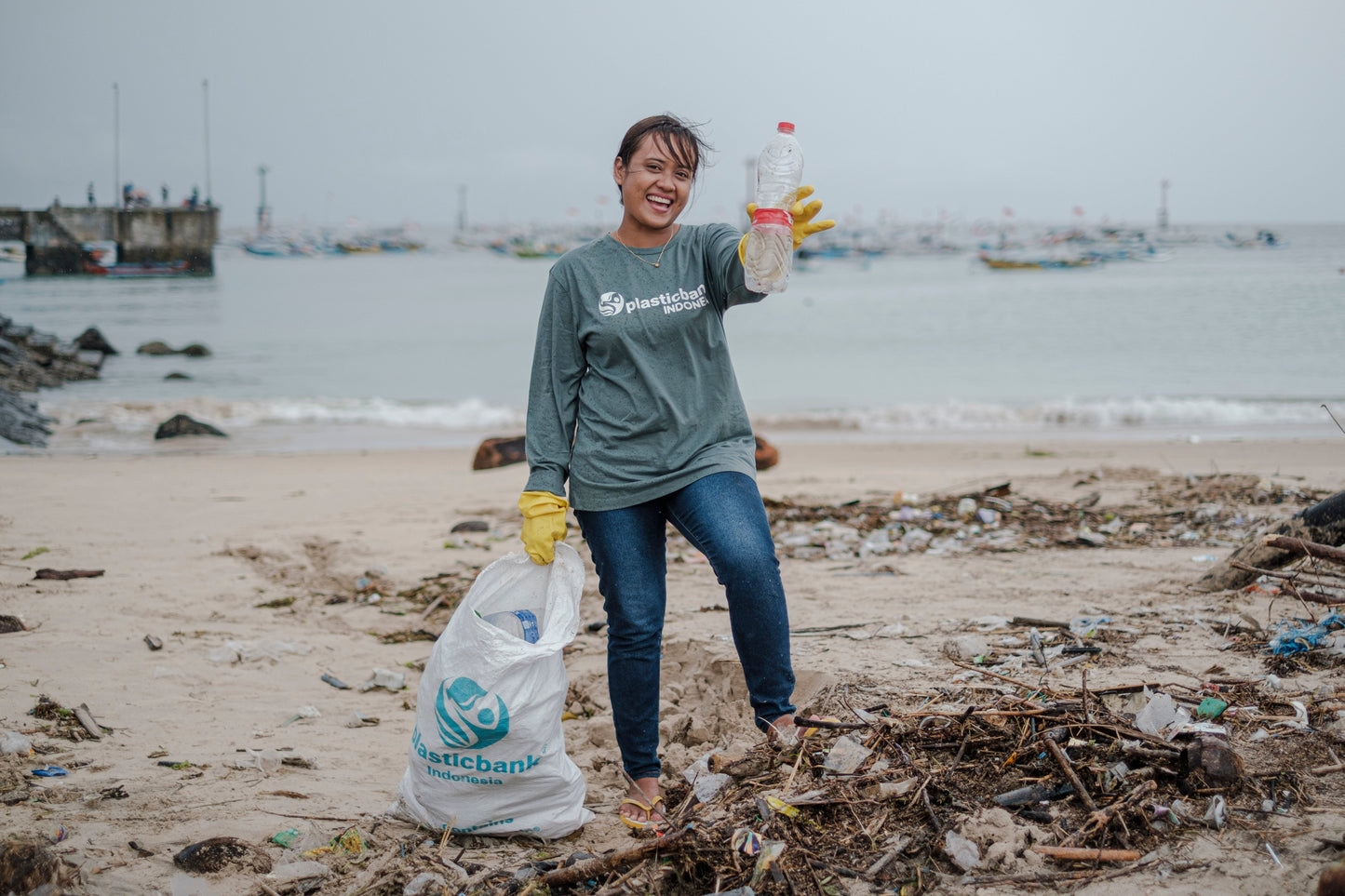 Ocean Bound Plastic - Persona raccoglie rifiuti di plastica sulla spiaggia per rimuovere bottiglie dirette verso l'oceano.