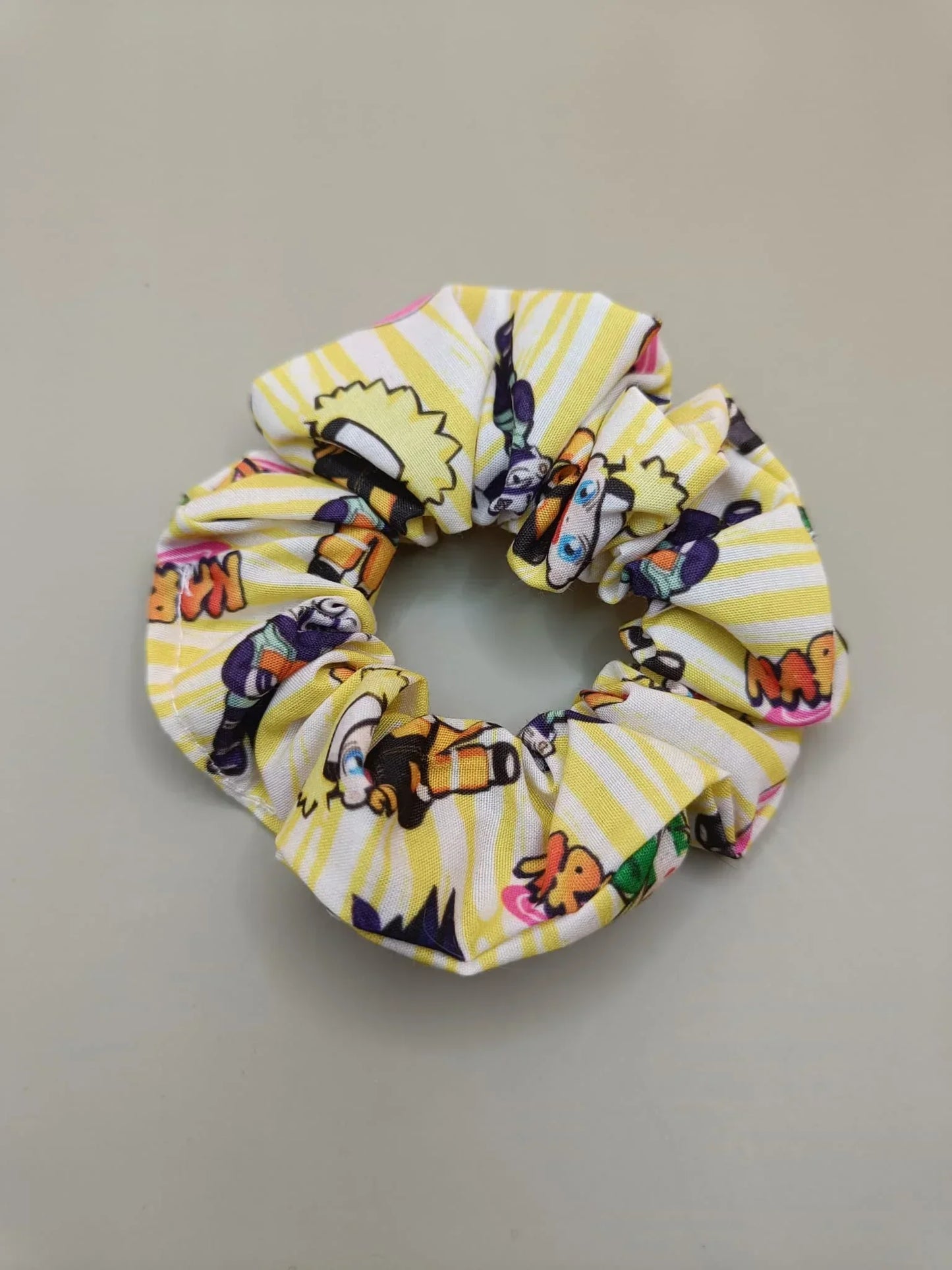 Scrunchie Naruto con personaggi chibi e sfondo giallo