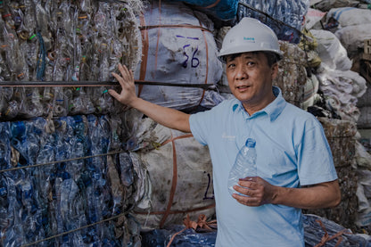 Ocean bound plastic - Persona accanto a balle di bottiglie di plastica riciclate, gesto per promuovere la rimozione di plastica legata all'oceano.