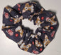 Lo scrunchie Gremlins Gizmo di L'Atelier di Zelda presenta un design fatto a mano con uno sfondo scuro che mette in risalto i motivi Gizmo e popcorn, aggiungendo un tocco giocoso a qualsiasi outfit.