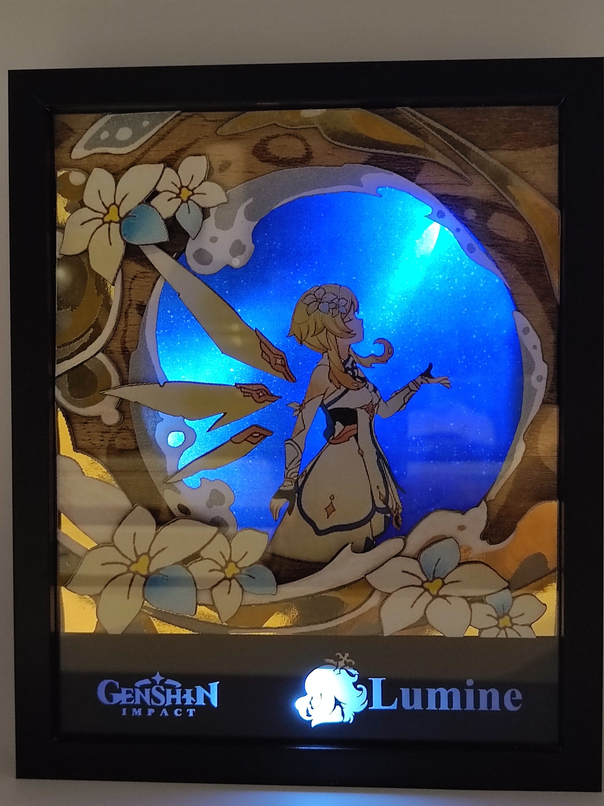 Lightbox Lumine accesa – Genshin Impact con sfondo blu luminoso e fiori bianchi
