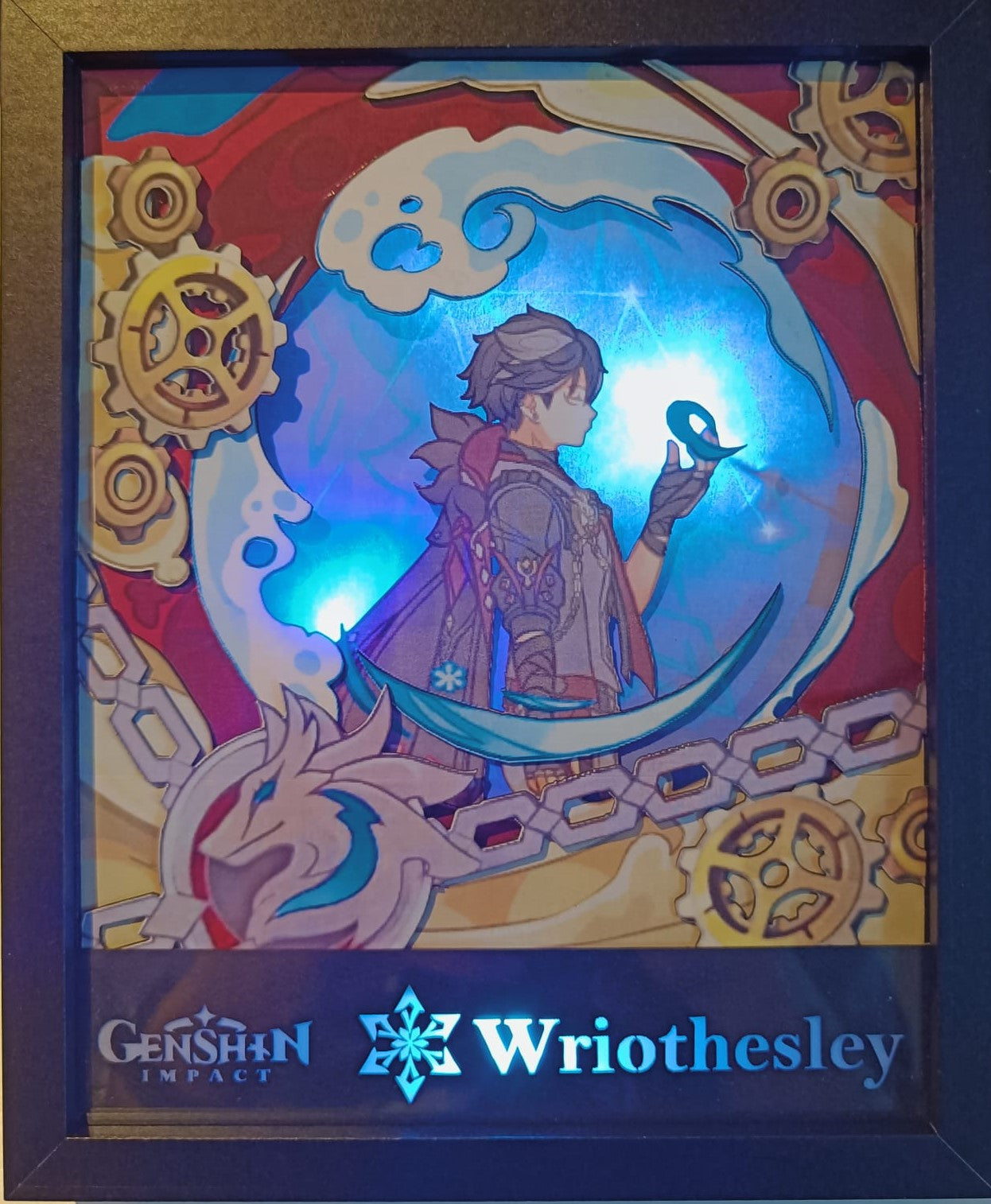 L'Atelier di Zelda presenta una cornice realizzata a mano raffigurante Wriothesley di Genshin Impact. L'immagine lo mostra di profilo contro ingranaggi e catene, mentre tiene in mano un globo luminoso. Le tonalità blu e rosse con dettagli illuminati creano un incantevole effetto lightbox di Wriothesley.